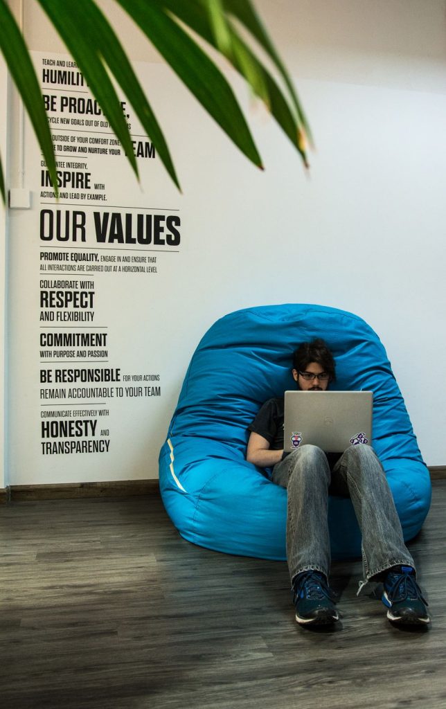 Photo of a software developer coding sitting on a puff couch