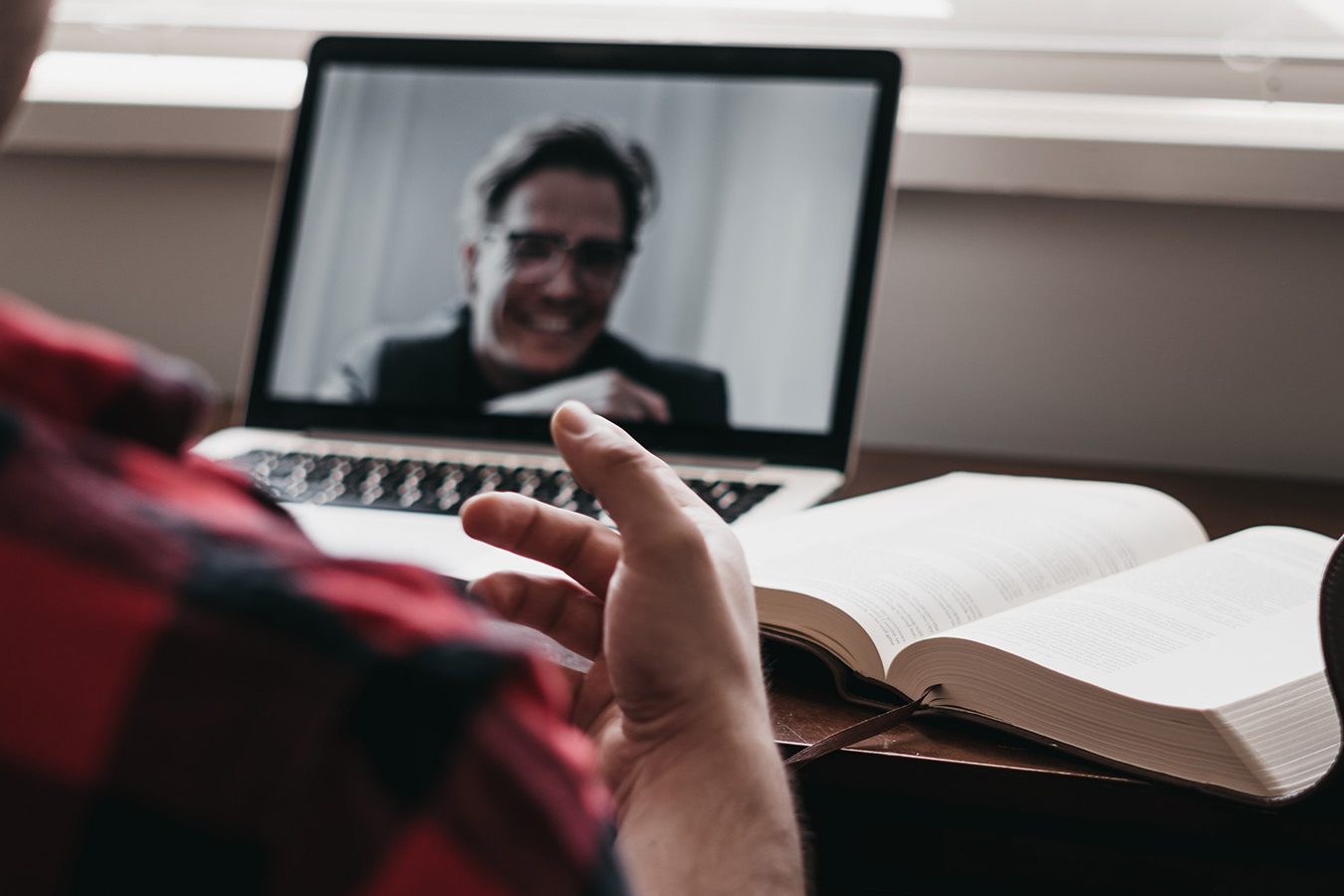 An image capturing a man engaged in a video call with a client, shown from behind.