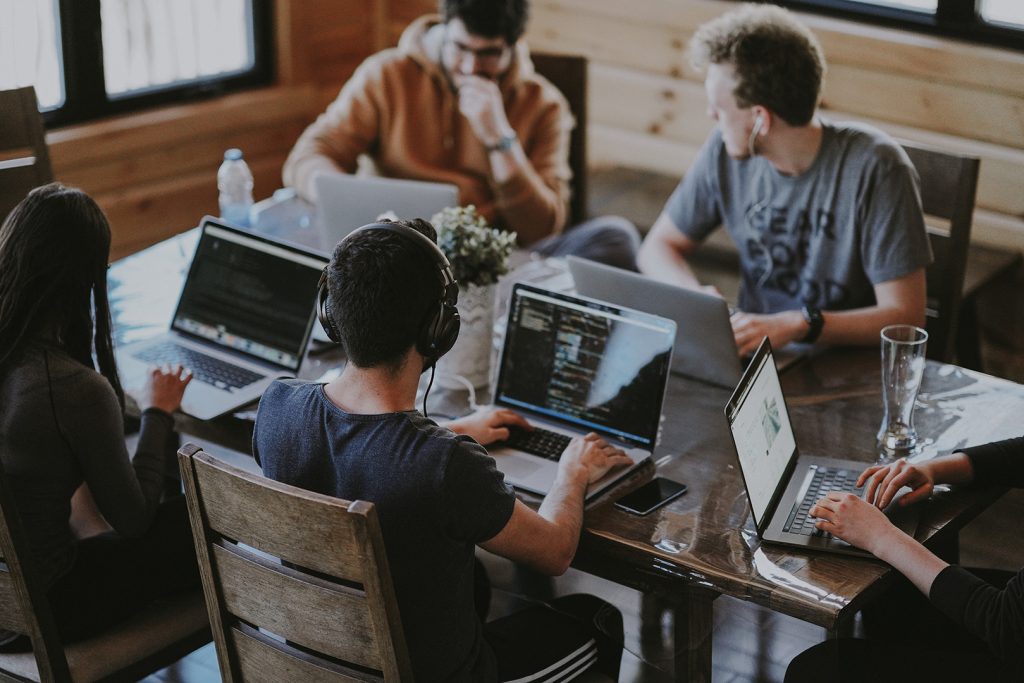 An image capturing a collaborative team effort as members work together on a project, each engrossed in their individual tasks on separate computers. The atmosphere is one of shared focus and teamwork.